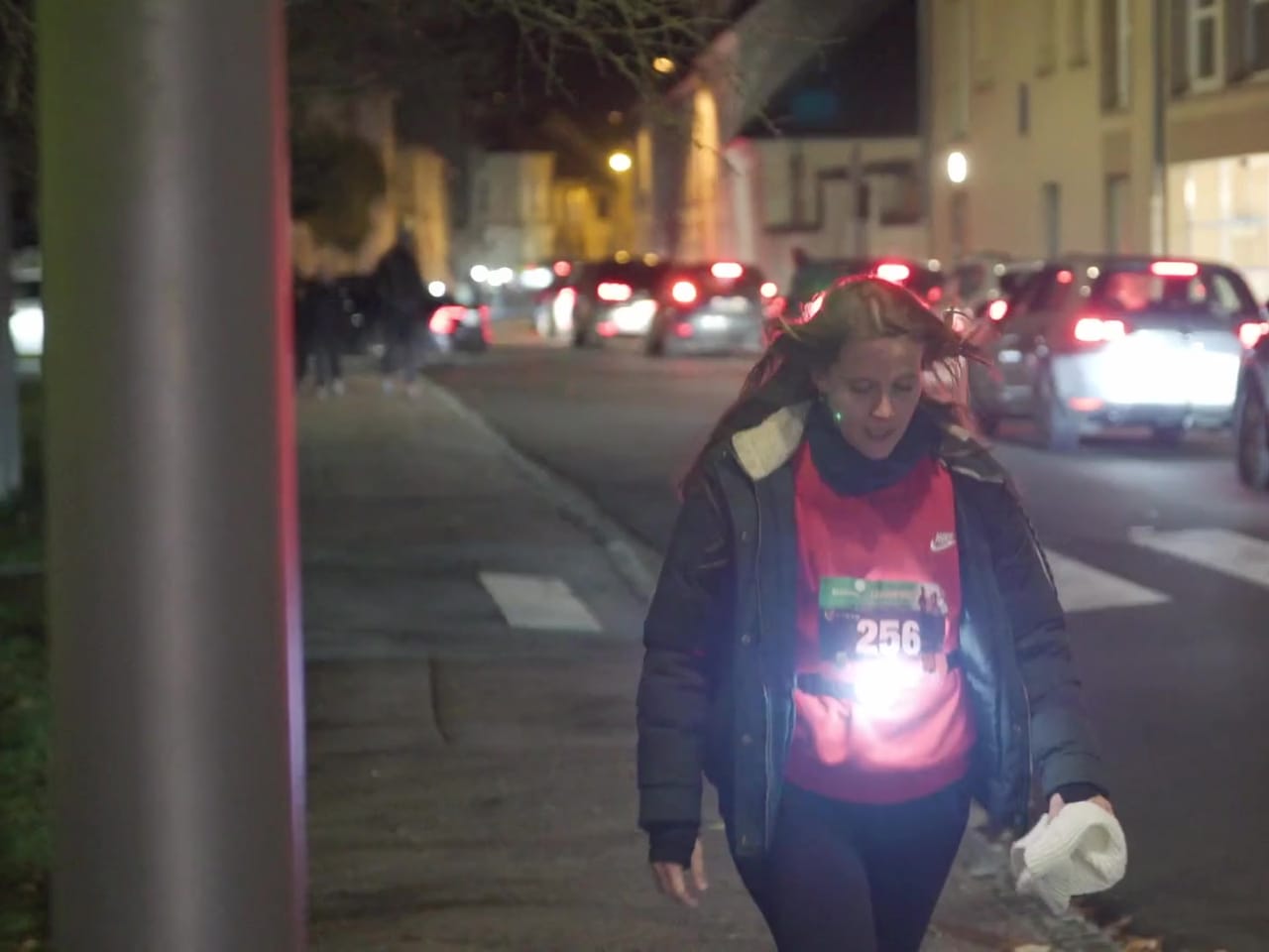 Participante d'une course nocturne, lampe frontale allumée, filmée en ville