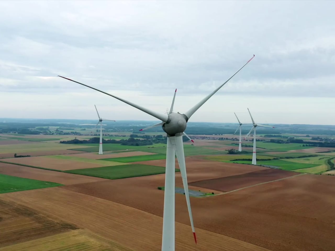 Éolienne filmée de face par drone, au-dessus des champs